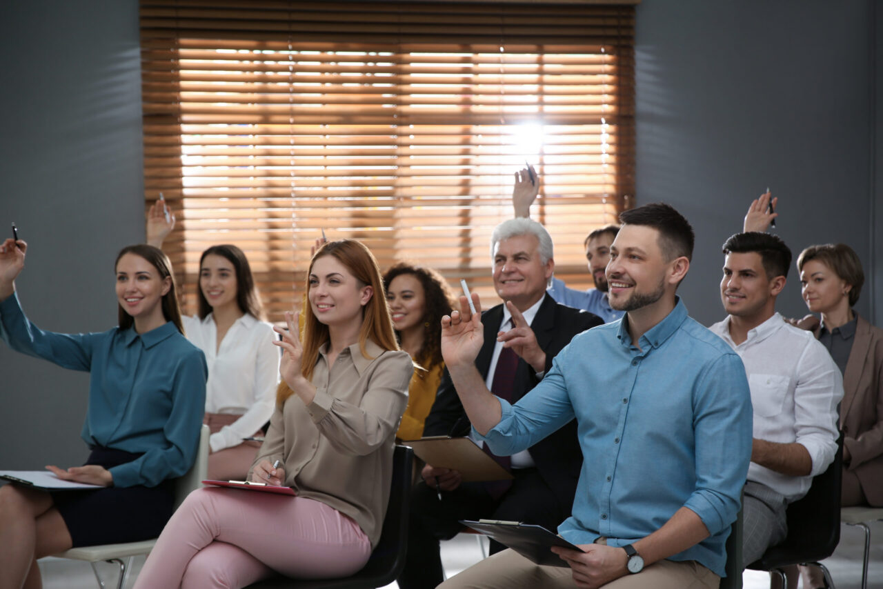 Attendees raising their hands to ask questions during an office training session