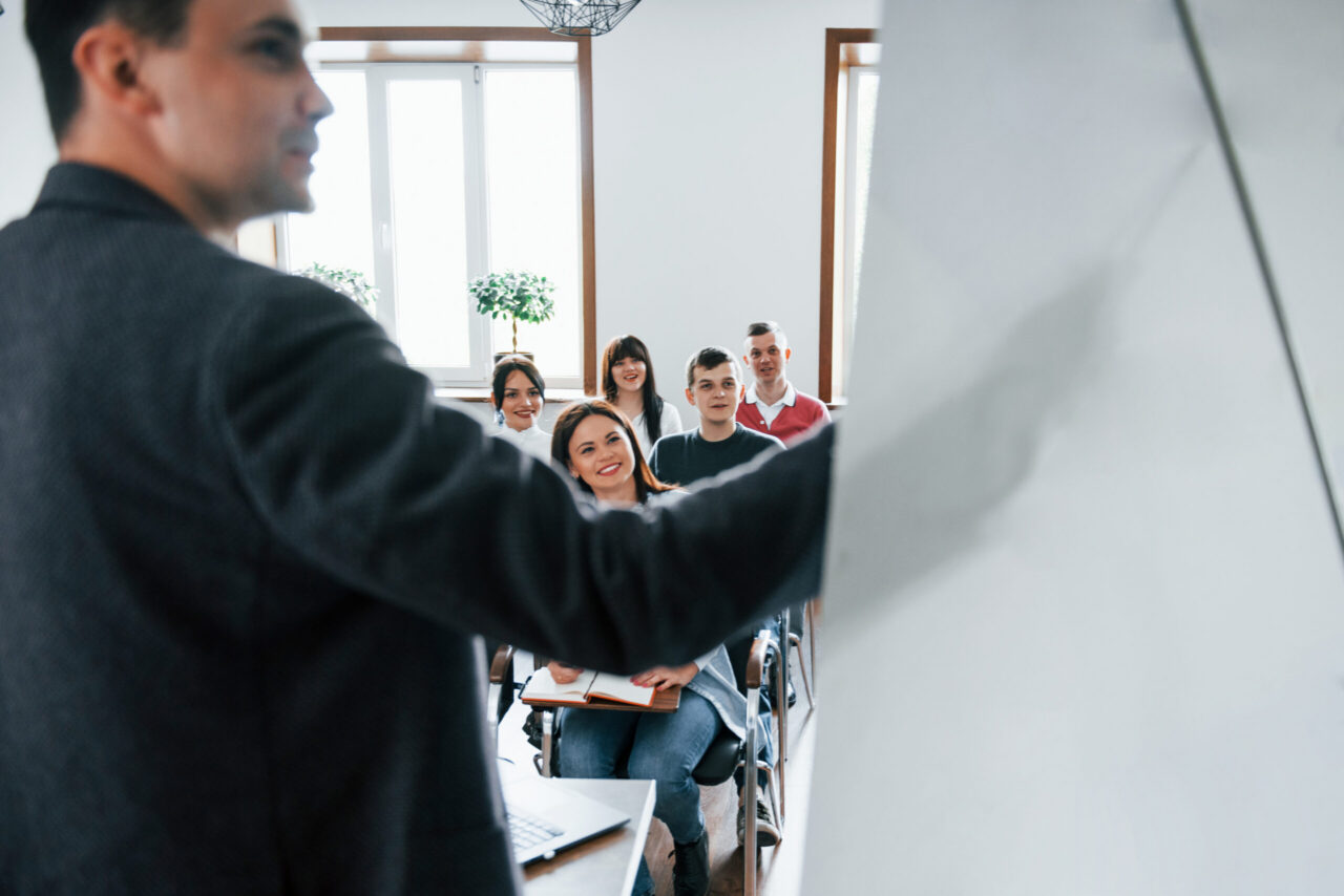 Instructor presenting data to a seated professional audience in a classroom
