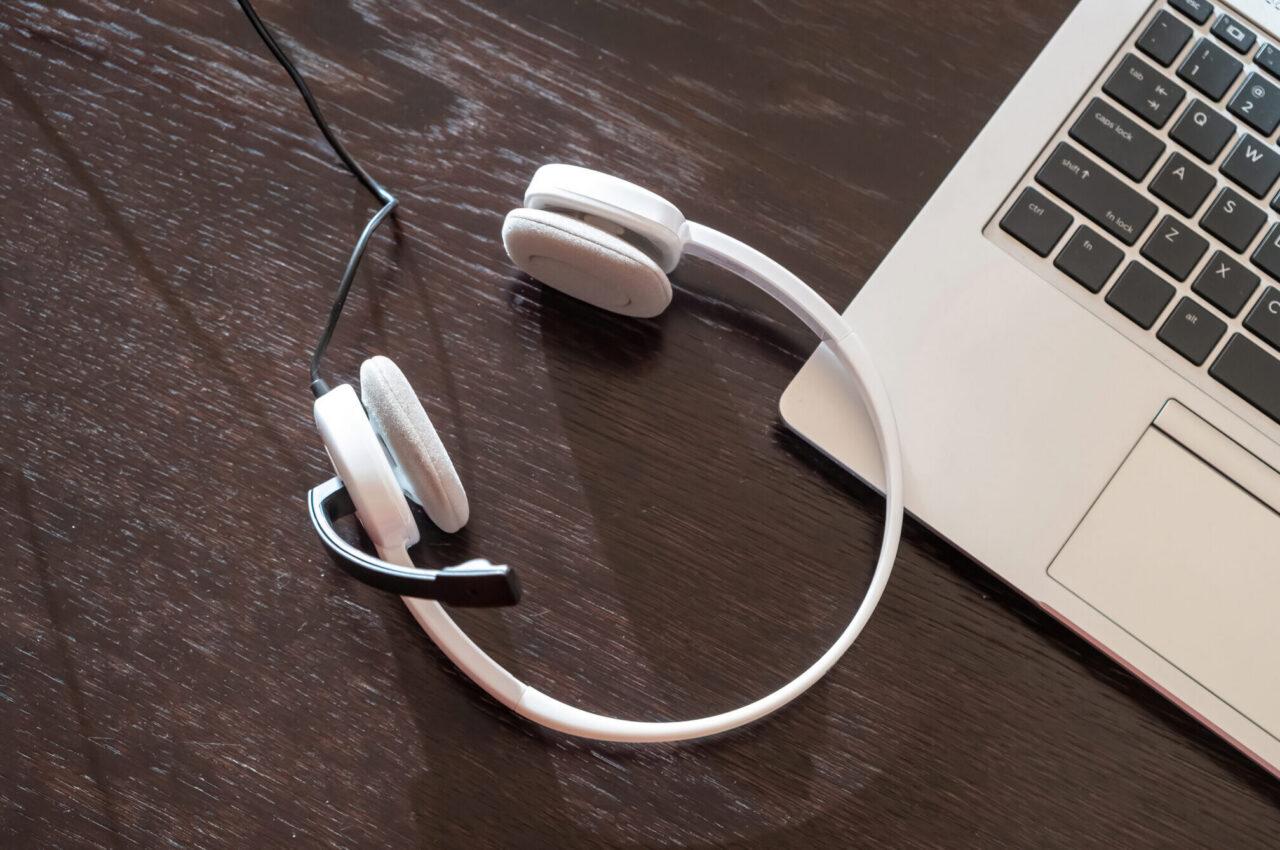 Laptop with a headset on a wooden desk, suggesting remote work and virtual calls