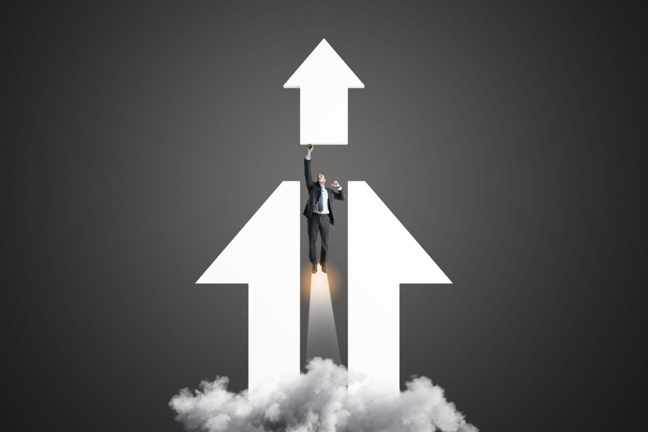 Businessperson rising upward between large arrows pointing up, suggesting growth