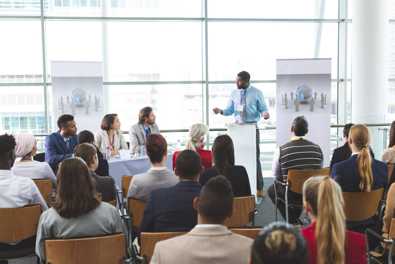 Presenter speaking to a large audience seated at a business conference
